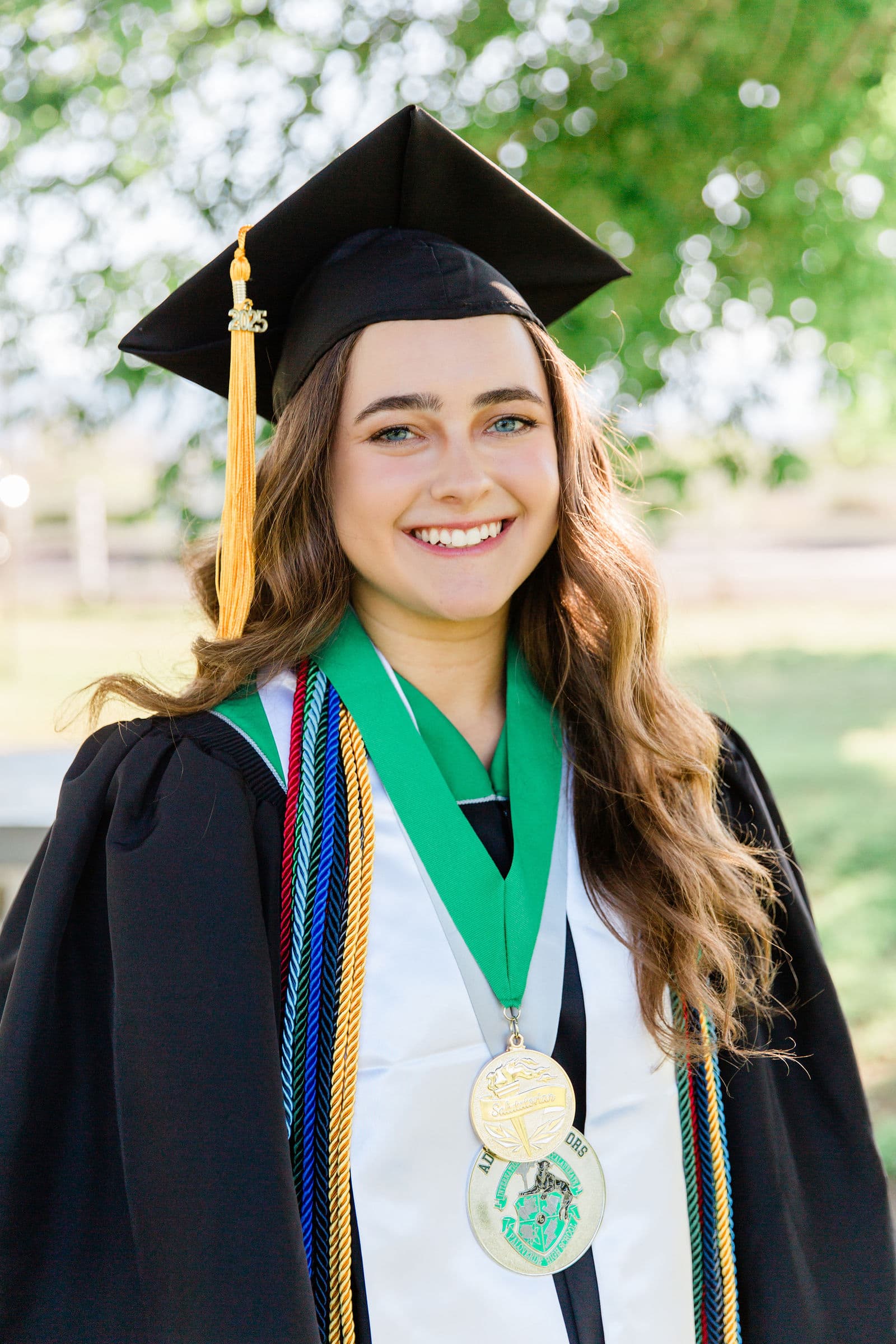 Senior in graduation cap gown medals and cords