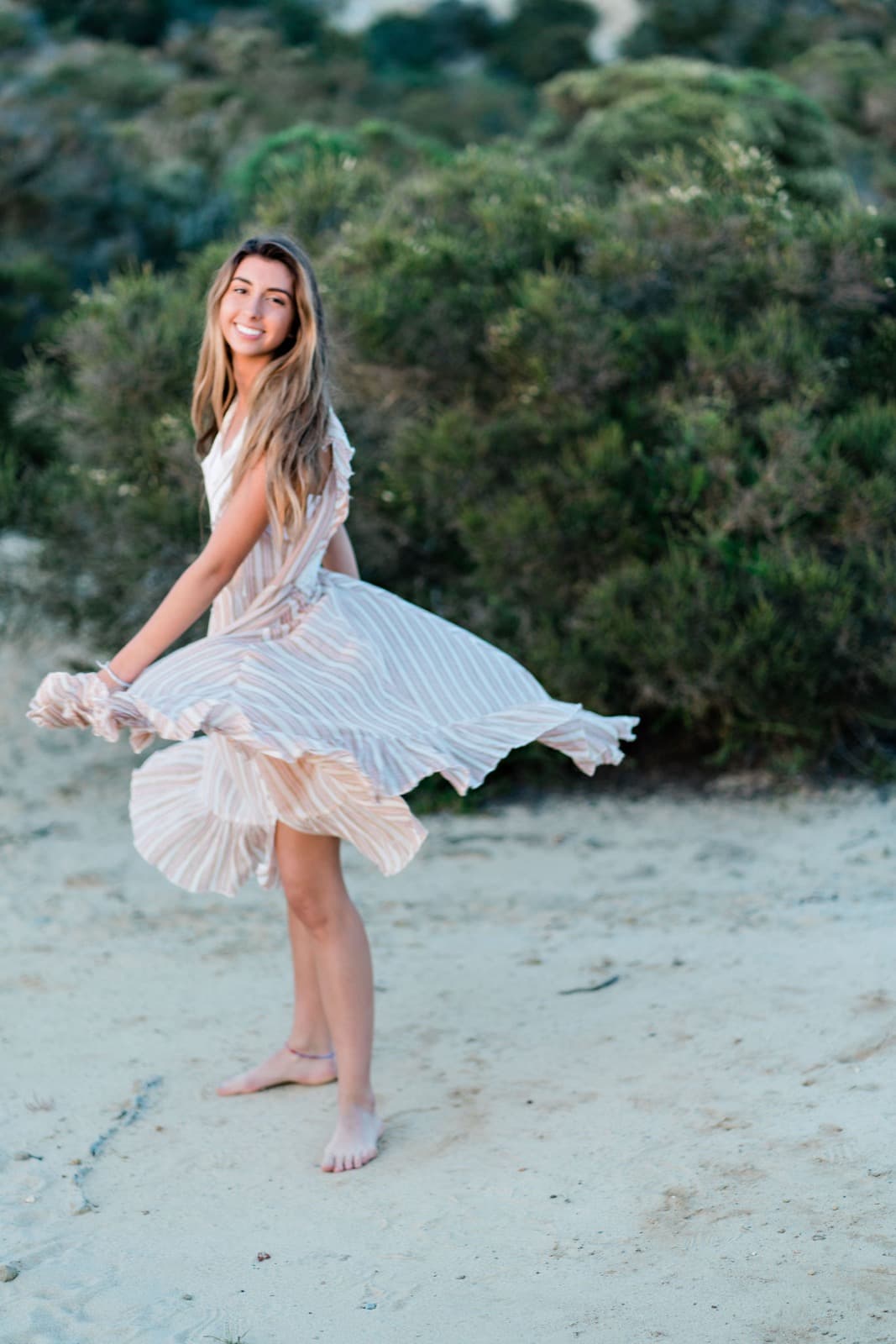 Senior girl twirling on sand