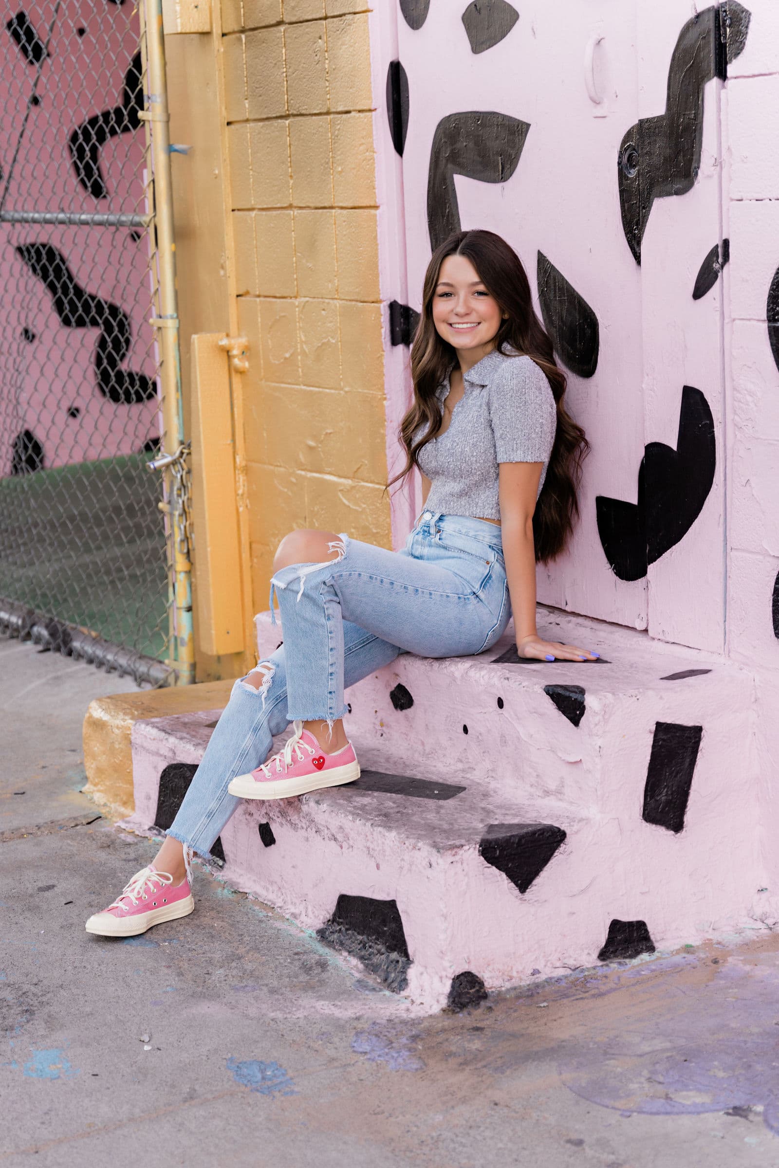 Senior girl gray polo pink sneakers at pink mural